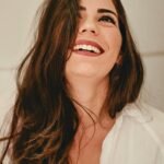 Portrait of a happy woman with long brunette hair and elegant style, expressing joy.